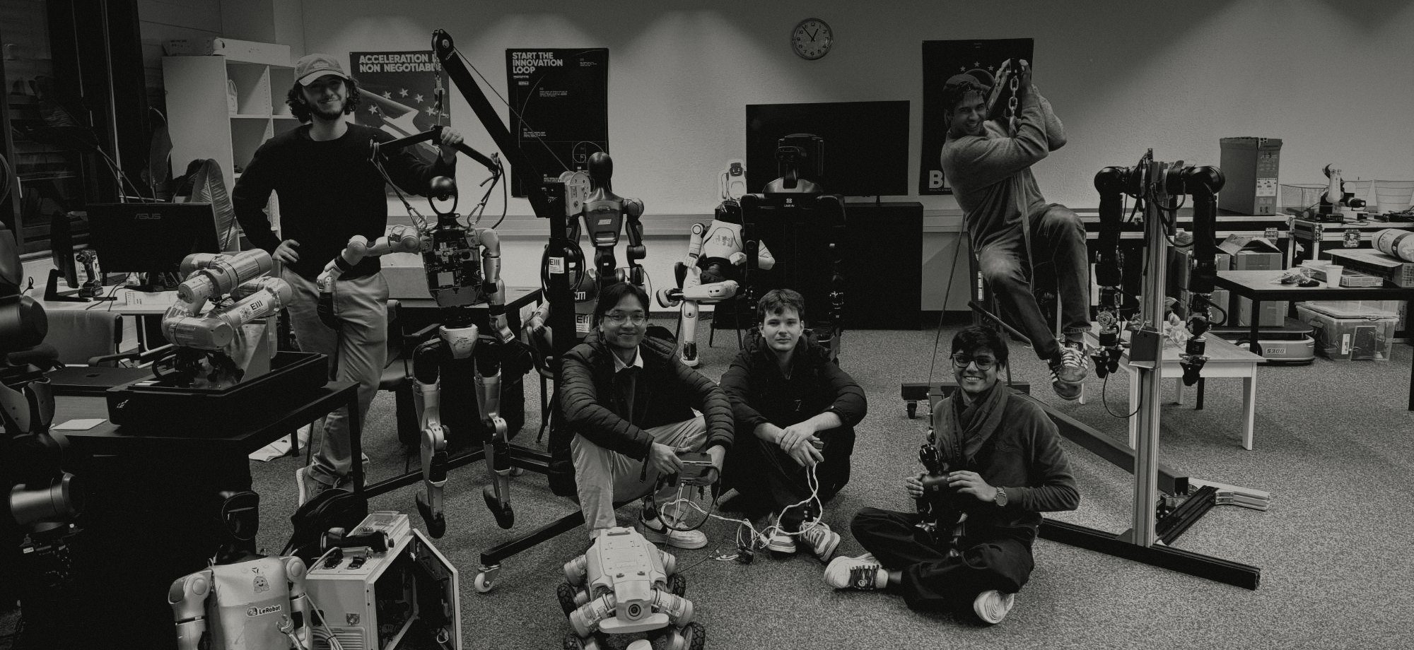 The team in the lab, between humanoid robots, robot arms and a quadruped
